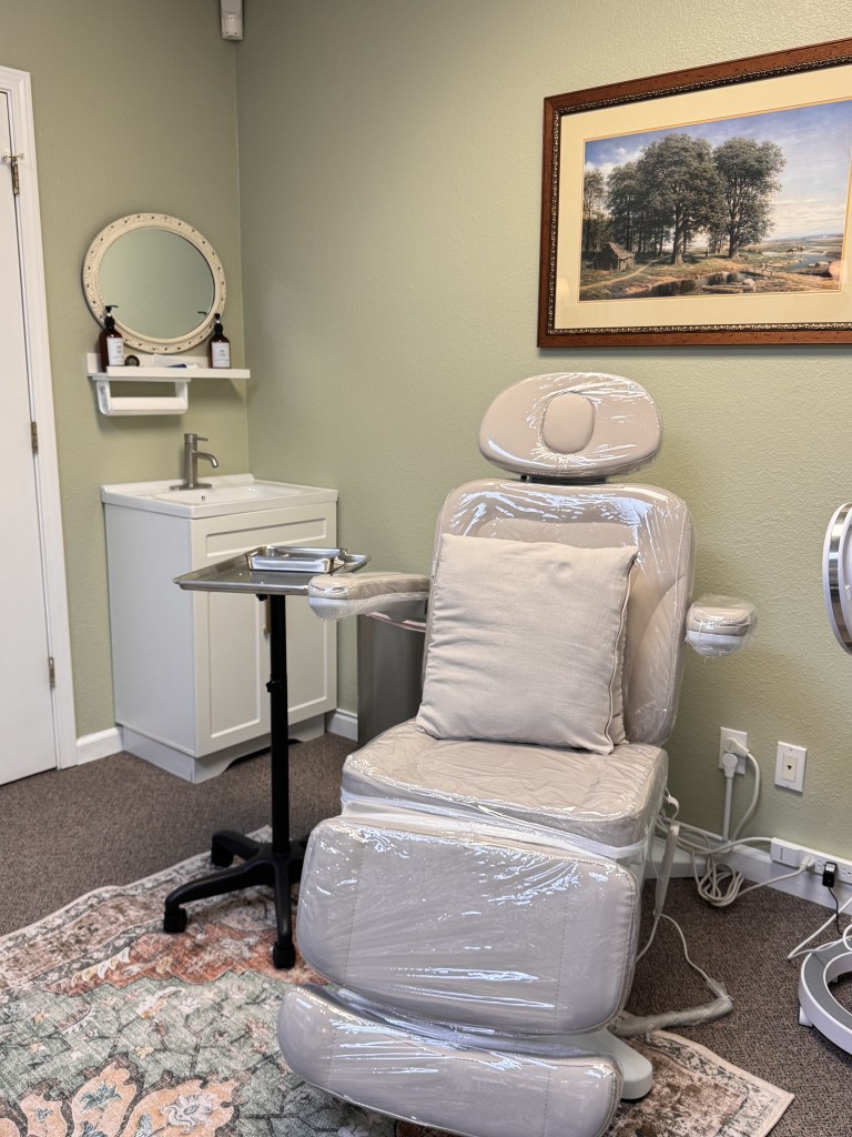 Side view of the cream treatment chair in the Wellness and Longevity treatment room in Old Roseville,with sink, mirror, and framed landscape art